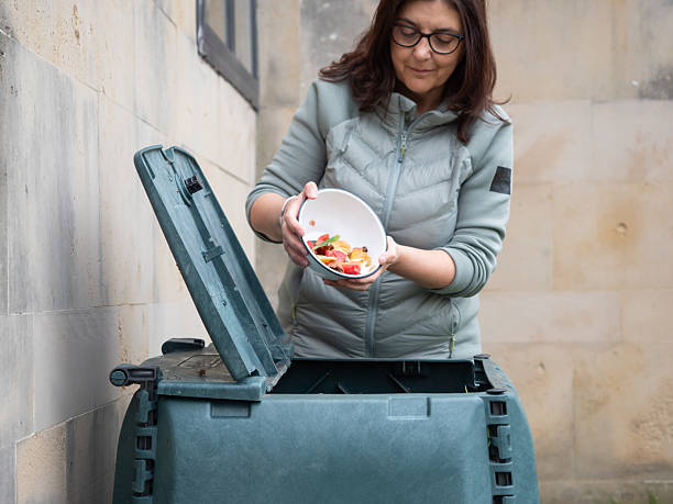 istock Woman throwing food scraps into compost bin for recycling 2217671008