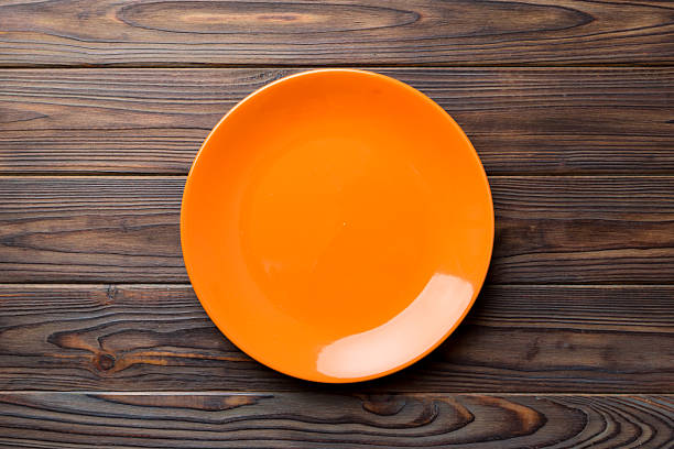 istock Top view of empty orange plate on wooden background. Empty space for your design 2217673455