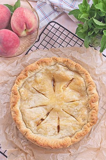istock Freshly baked old fashioned deep dish peach pie cooling on baking rack, vertical top view 2217674457