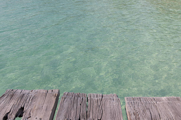 istock Old wood bridge floor with clear water. 2217674634
