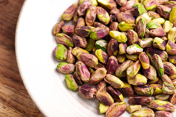 istock Roasted peeled pistachio kernels in ceramic bowl on wooden table 2217674768