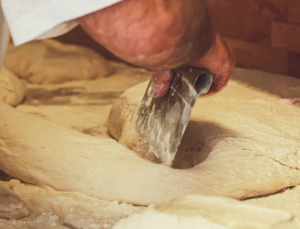 istock Baker dividing dough with metal scraper in bakery 2217675509