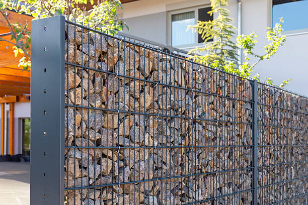 istock A modern gabion fence constructed from stones creates an elegant boundary. It stands in a contemporary setting, complemented by greenery and a sleek architectural backdrop, showcasing innovation 2217675539