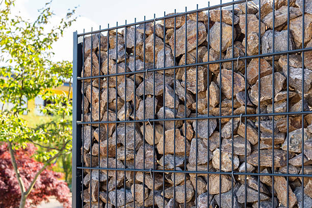 istock A modern gabion fence constructed from stones creates an elegant boundary. It stands in a contemporary setting, complemented by greenery and a sleek architectural backdrop, showcasing innovation 2217675658