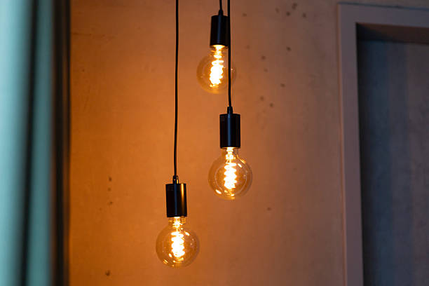 istock Three vintage-style light bulbs dangle from black cords in a modern indoor setting, casting a soft, warm glow against a stylish backdrop in the evening 2217676720