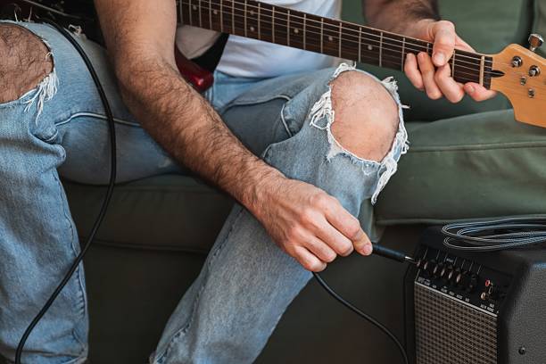 istock Musician plugging electric guitar into amplifier at home 2217680328