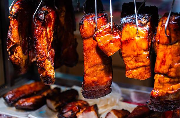 Rows of glazed char siu pork hanging vertically in a Chinese deli window, rich in color and caramelized texture.