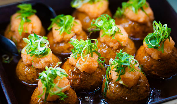 Japanese takoyaki drenched in savory sauce and topped with grated daikon and finely chopped green onions.