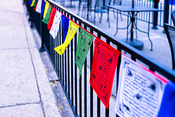 Tibetan Prayer Flags Lining Outdoor Cafe Area - Colorful flags in a row with selective focus on foreground with blurred background.