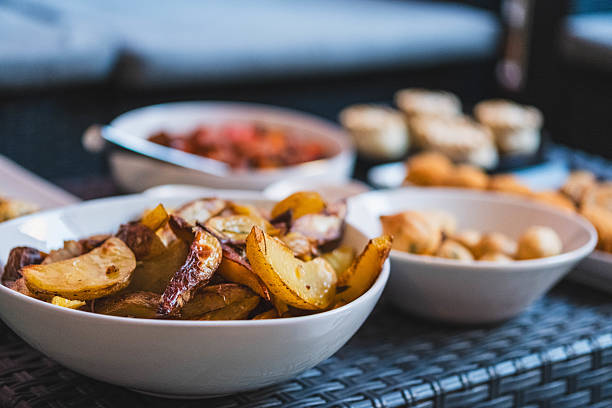 A close-up shot of golden brown potatoes sizzling on a grill, their surfaces glistening with oil and seasoned with herbs.