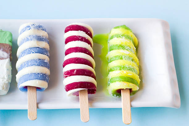 Colorful,frozen stick ice creams on the white long plate on light blue color background,half view