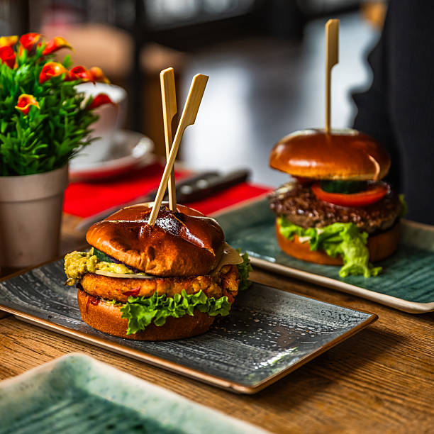 Veggie Burger on a wooden table in a restaurant, meat burger in the background