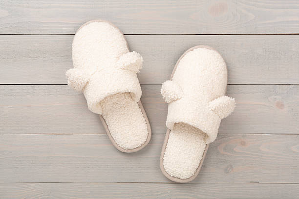istock Soft teddy slippers on wooden background, top view 2217689253