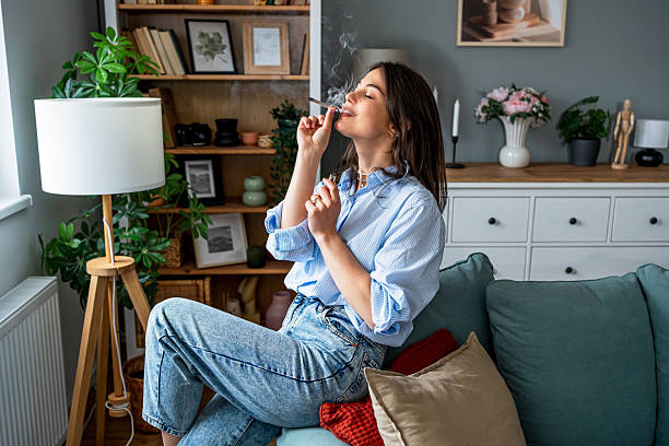 istock Young woman relaxing on sofa smoking marijuana joint at home 2217693698