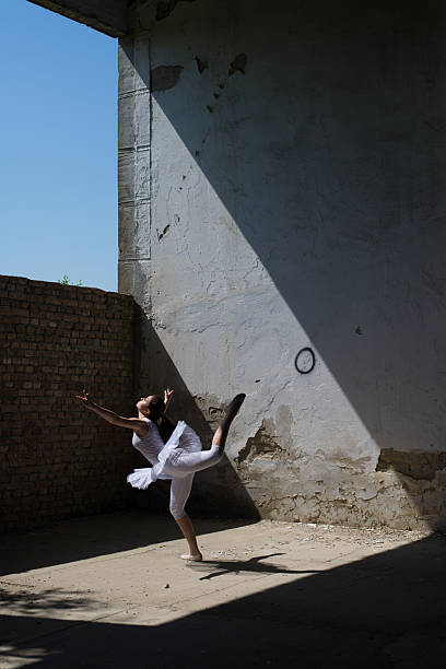 istock Young ballerina in white tutu dancing in abandoned building 2217693763