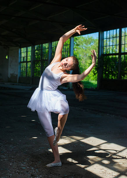 istock Young ballerina in white tutu dancing in abandoned building 2217693776