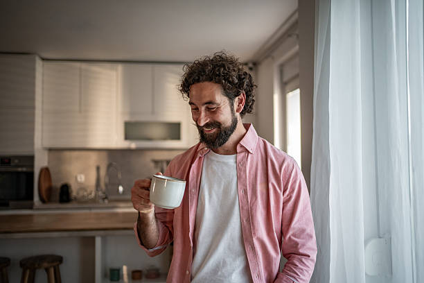 istock Smiling man enjoying a cup of coffee in his kitchen 2217700143