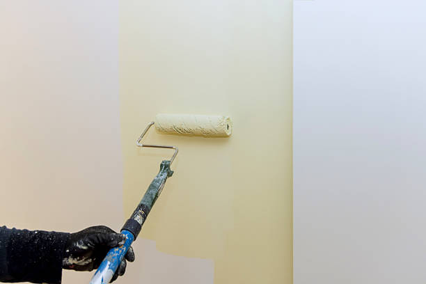 istock Home improvement project with person painting wall in light color using roller in contemporary space 2217702673