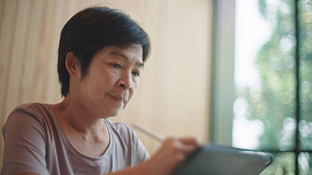 istock Mature woman writing on digital tablet. 2217702975
