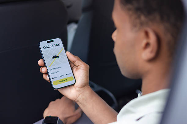 istock Young passenger requesting taxi ride using mobile app in car 2217705870