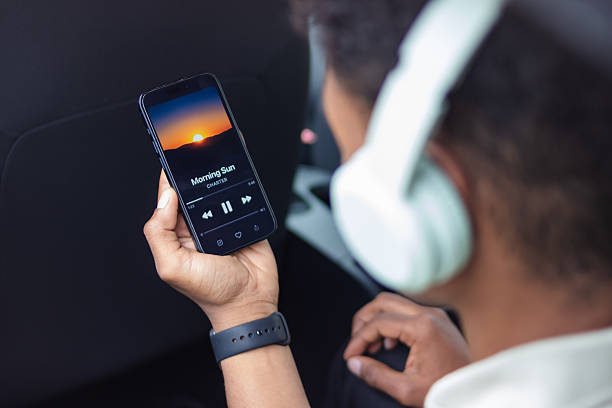 Young man listening to music on his smartphone while traveling by car