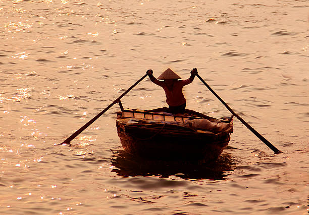 Vietnam Hanoi, Halong bay  woman rowing small boat at sunset