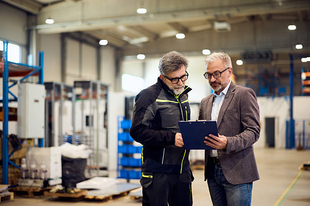 istock Two Business Professionals Discussing Documents in a Modern Industrial Facility 2217709500