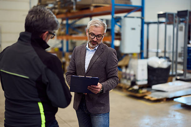 istock Manager Discussing Logistics with Worker in Warehouse Facility 2217709516
