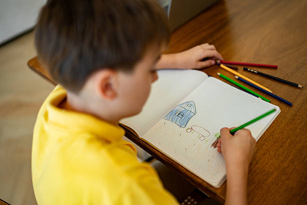 Child boy drawing on note pad at home