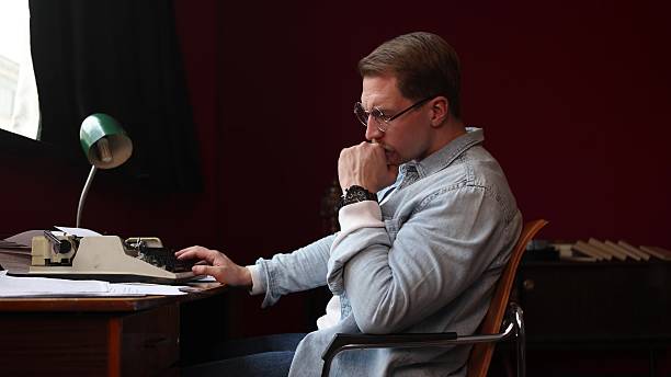 istock Soft-focused image of a writer struggling with creativity at his cluttered desk, 2217712757