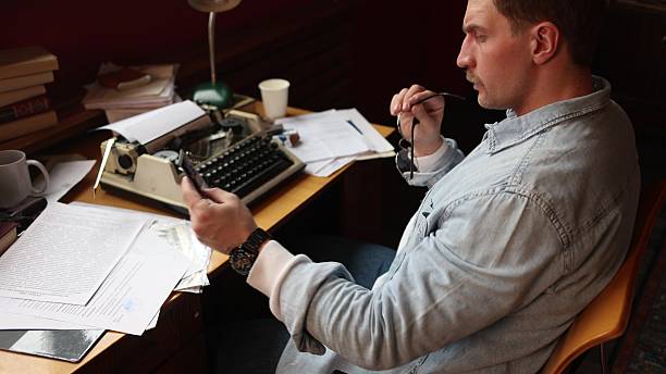 istock Frustrated young journalist smokes at vintage typewriter, cinematic 2217713193