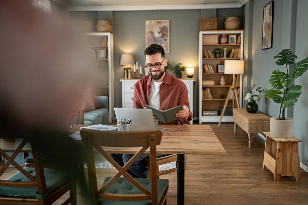 istock Young man working from home reading a book and smiling 2217715668