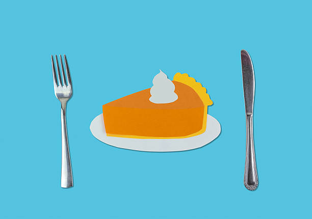 Pumpkin pie slice from cutout paper with fork and knife silverware on a blue background with copy space