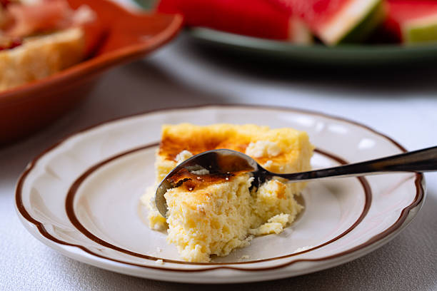 Close-up of a spoon taking a bite from a slice of homemade cheesecake on a plate