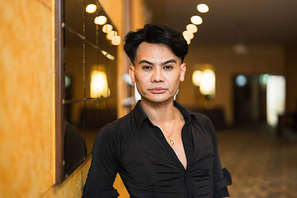 Portrait of a male dancer in black costume standing at dance studio with contented emotions looking at camera.