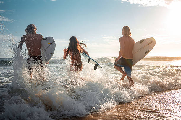 istock Joyful Friends Surfing Running into Sunrise Waves 2217727145