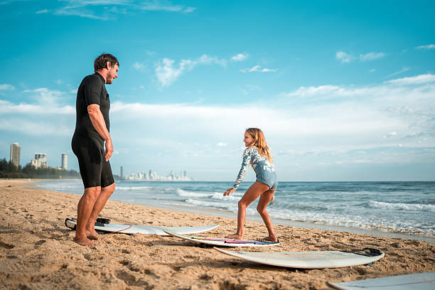 istock Caucasian Father Teaching Young Daughter Surfing at Beach 2217727149