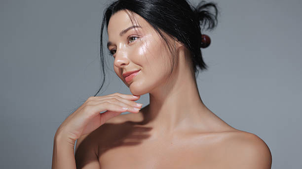 istock Elegant Woman With Glowing Skin Touching Face In Soft Shadowed Studio Light 2217737777