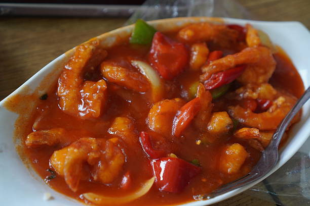 A captivating culinary close-up of sweet and sour shrimp, showcasing the rich colors and inviting textures of this popular seafood delicacy. This image tells a story of authentic Asian cuisine, perfect for editorial features on global food trends, healthy eating, or the art of home cooking. It conveys warmth, comfort, and the joy of a flavorful meal.