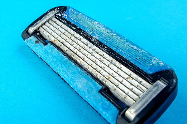 A close-up of a disposable razor with a blue handle and purple lubrication strip.