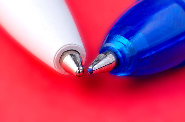 Two ballpoint pens in macro close-up on red background