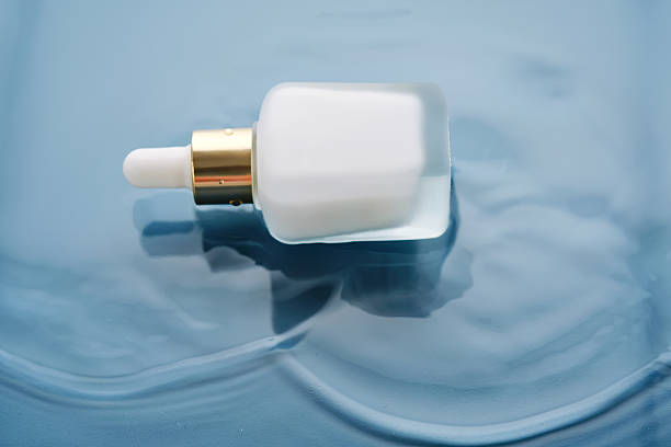 istock Bottle with white moisturizing serum in water on blue background. 2217747772