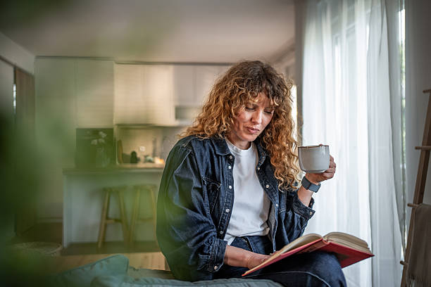 istock Woman relaxing at home reading a book and drinking tea 2217748045