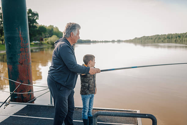 istock Grandfather teaching grandson how to fish on a lake 2217754540