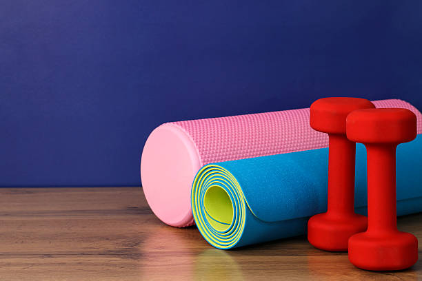 istock Foam roller, exercise mat and dumbbells on wooden surface promoting healthy lifestyle 2217755786