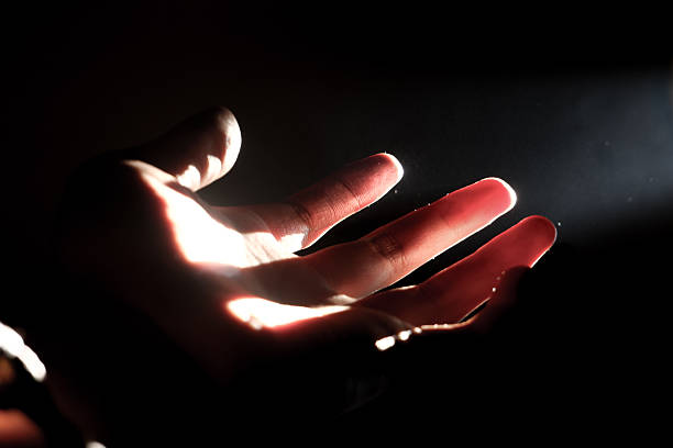 istock Human Hand Reaching Towards Sunlight Through Curtain in Dark Room 2217755819