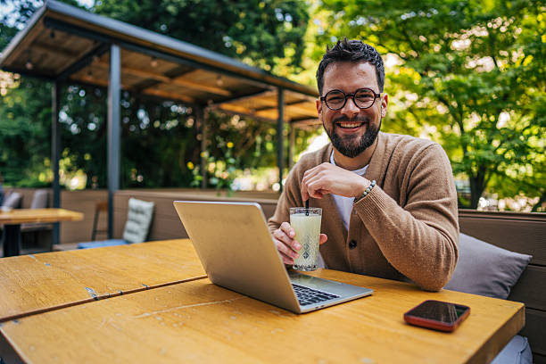 istock Freelancer enjoying a lemonade while working on his laptop in an outdoor cafe 2217758913