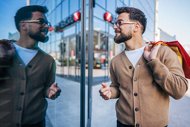 istock Young man smiling and looking at his reflection after shopping spree 2217759787