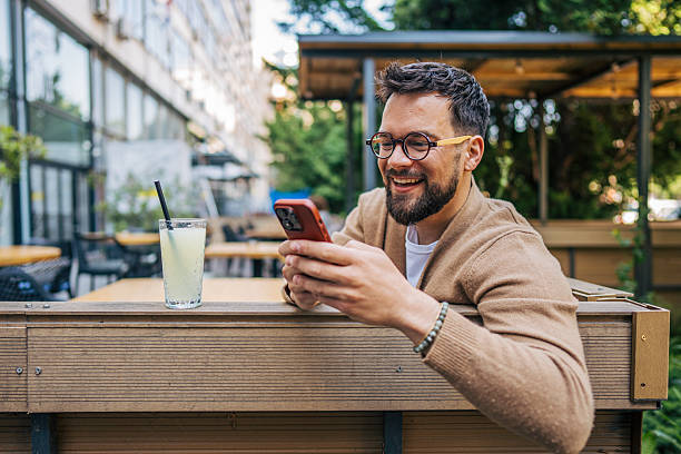 istock Smiling man using smartphone at outdoor cafe, enjoying a refreshing drink 2217759865
