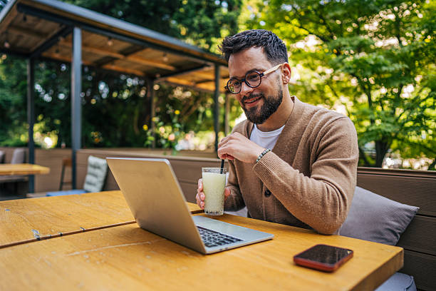 istock Freelancer enjoying a refreshing drink while working on laptop at outdoor cafe 2217760084